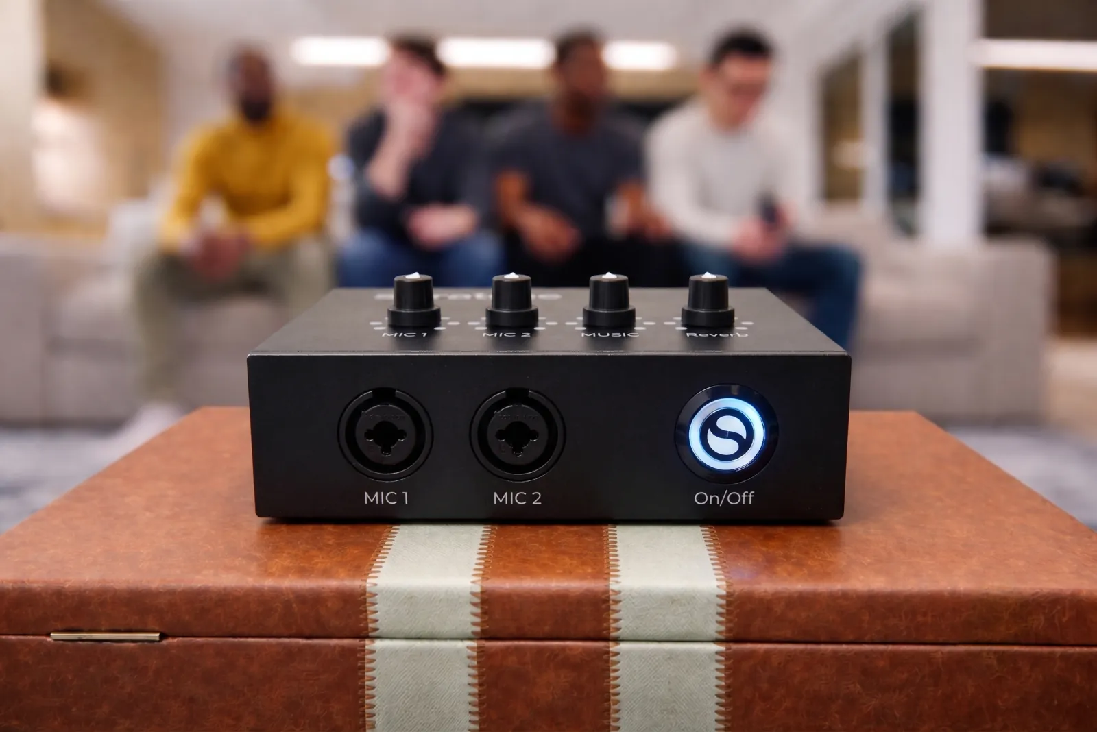 Seratone Karaoke on a side table with its power ring lit, friends sitting on a couch behind it
